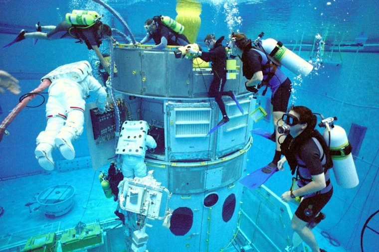 People in scuba gear and space suits in a pool